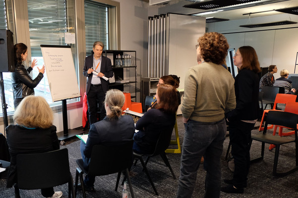 Thorsten Halling und Annegret Dreher stehen an einem Flipchart und diskutieren mit Teilnehmer*innen.