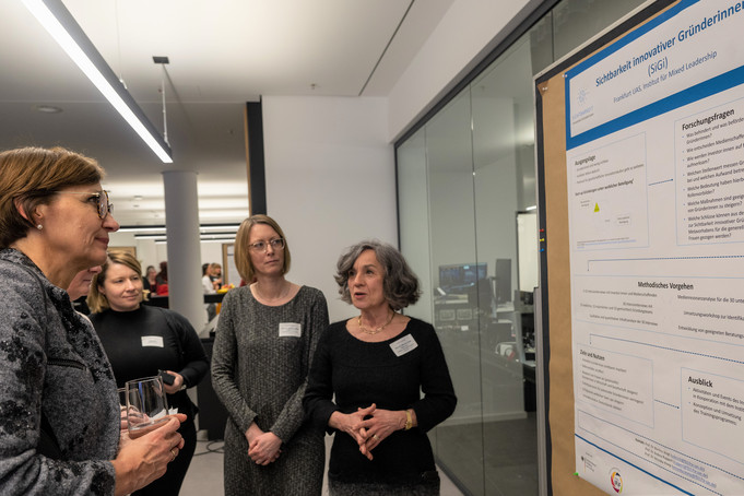 Die Ministerin und zwei weitere Frauen schauen sich ein Poster an.