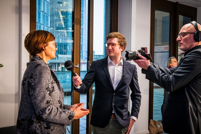 Die Ministerin wird von einem Reporter und einem Kameramann interviewt.