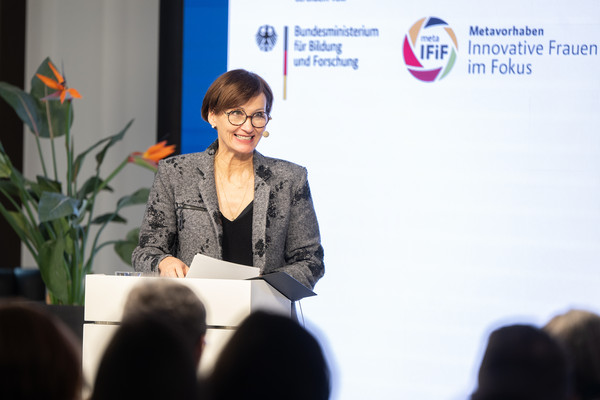 Bundesforschungsministerin Bettina Stark-Watzinger eröffnet die Veranstaltung. Bundesforschungsministerin Bettina Stark-Watzinger steht an einem Rednerpult und spricht zum Publikum.