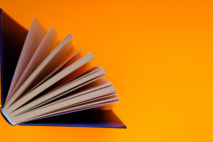 Halb aufgeklapptes Buch auf orangem Hintergrund
