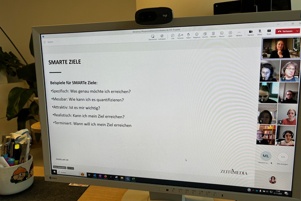 Ein Monitor mit einer Folie, auf der die Abkürzung SMARTE Ziele erläutert wird.